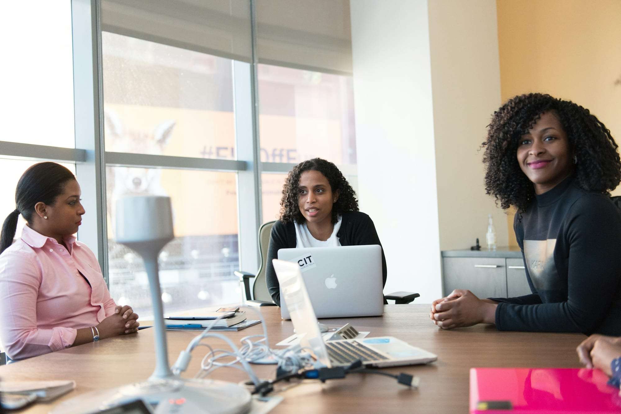 Three professionals in a meeting around a conference table