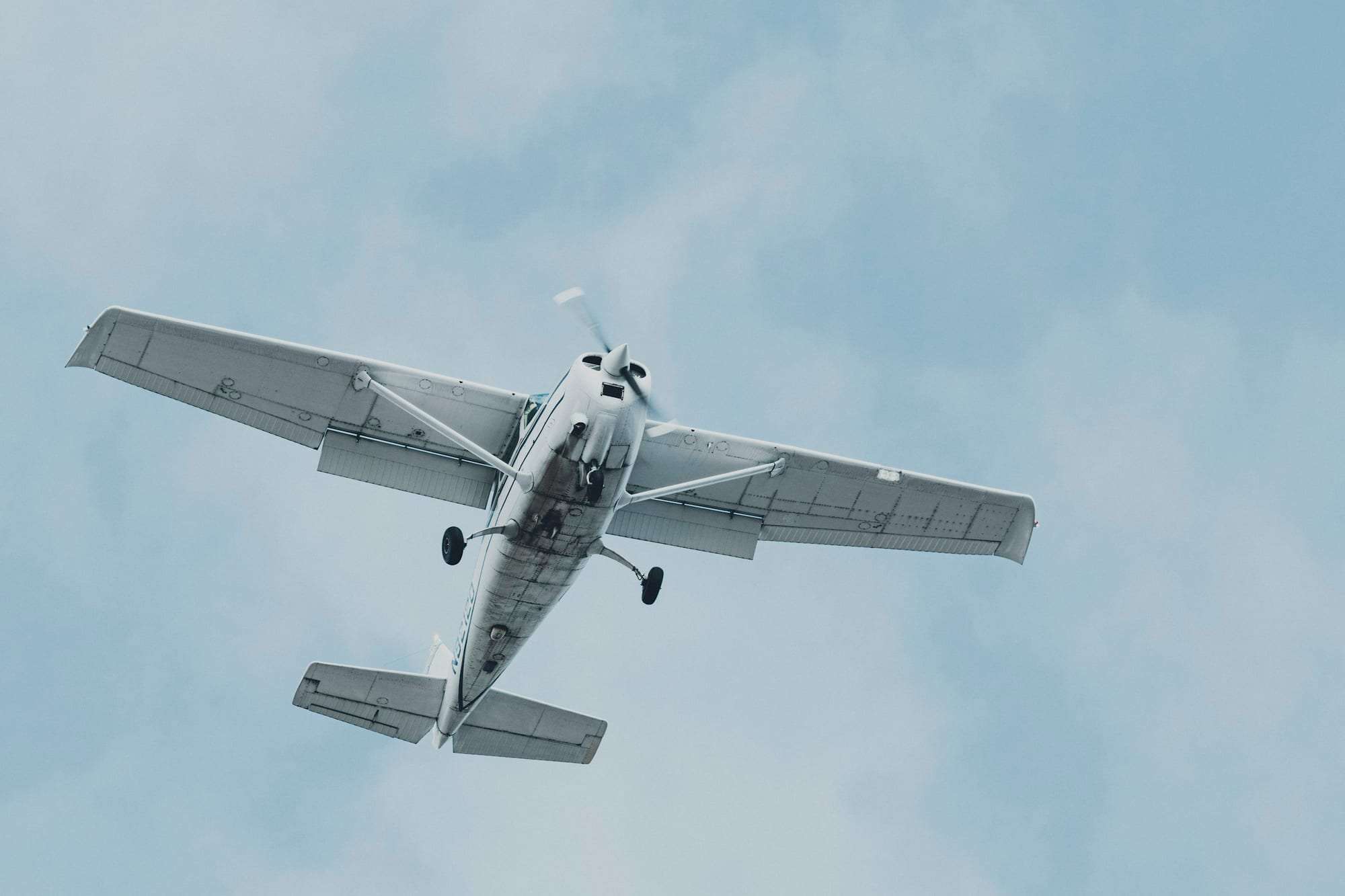A light training aircraft in flight, seen from below