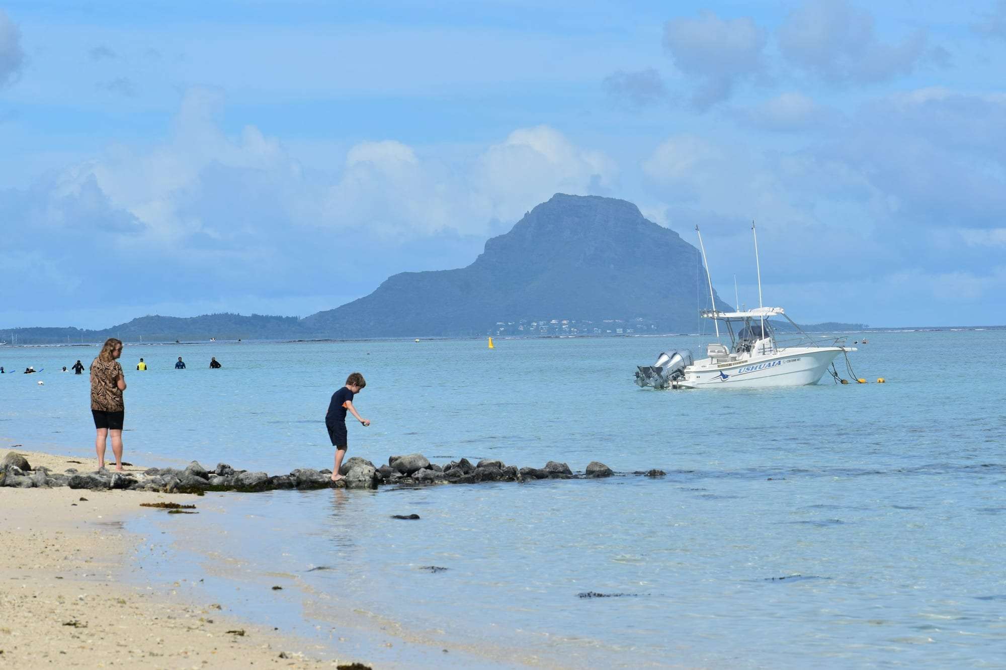 People on the shore at Flic en Flac, Mauritius, with mountains across the water